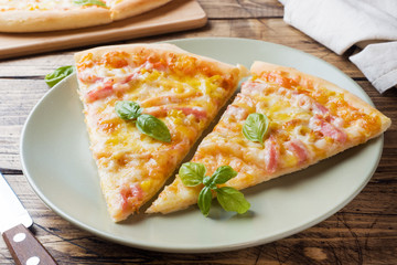 Pieces of homemade pizza on a plate on a wooden table.