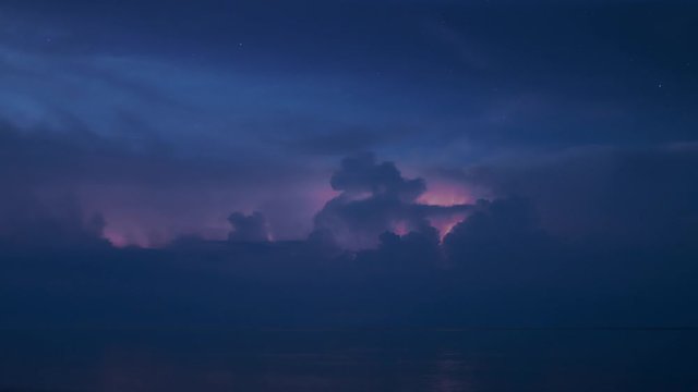 Night storm with many lightnings and starry sky far on horizon above a lake long exposure timelapse