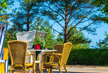 Obraz premium blue white beach chair with a table and chairs against a background of trees and blue sky in the sunshine