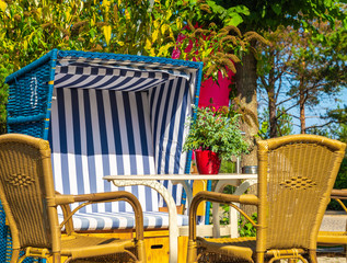 blue white beach chair with a table and chairs against a background of trees and blue sky in the sunshine