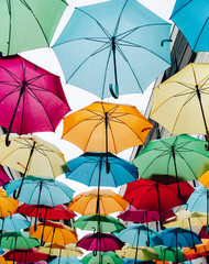 Fototapeta na wymiar Arrangement of multicolored umbrellas in a row against the sky