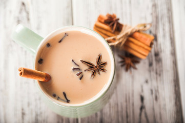 Details of still life in the home interior living room. Beautiful Cup of tea with milk, star anise, cinnamon on a wooden background. Cozy autumn-winter concept. Masala is a traditional hot spicy drink