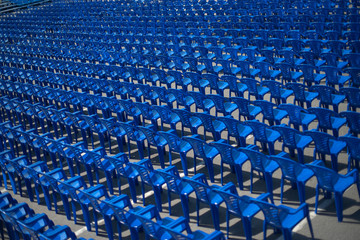 blue chairs stand on the street for a concert.