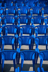 blue chairs stand on the street for a concert.