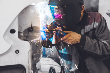 Worker welds car body with carbon dioxide welding. Weld of vehicle.