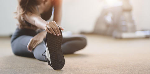 Beautiful Asian woman with tan and slim body stretching legs before exercise - obrazy, fototapety, plakaty