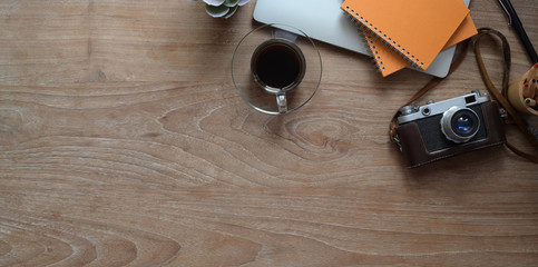 Top view of modern rustic workplace with laptop computer, camera and office supplies