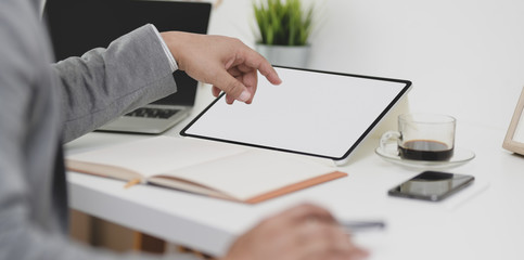 Cropped view of professional businessman working on his project with blank screen tablet in modern office