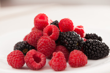 handful of raspberry and blackberry berries on white background