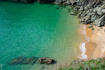 A natural paradise of crystal clear aqua sea with waves breaking on a deserted cove with bright...