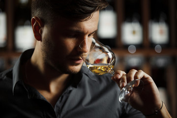 Bokal of white wine on background, male sommelier appreciating drink