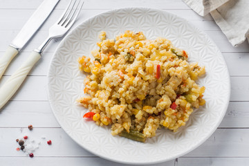 Pilaf with vegetables and chicken in a gray plate on a light background.