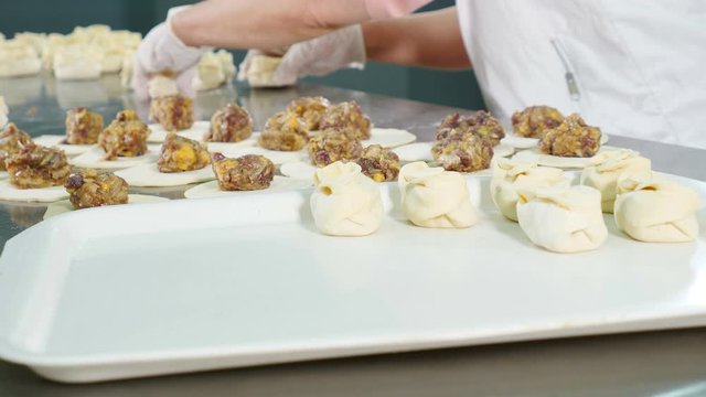 Food video concept. Chef making khinkali. National Georgian cuisine. Close up. Putting ready made Dumplings on tray. 4k