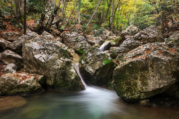 Amazing Autumn landscape. River in colorful autumn park with yellow, orange, red, green leaves. Golden colors in the mountain forest with a small stream. Season specific.