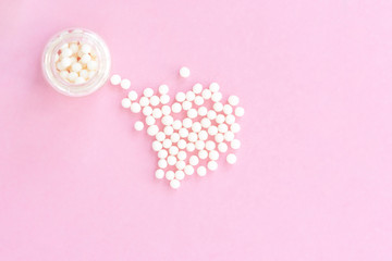 Homeopathy eco medicine concept - classical homeopathy pills in vintage glass bottles on pink background. Flatlay. Top view. Copyspace