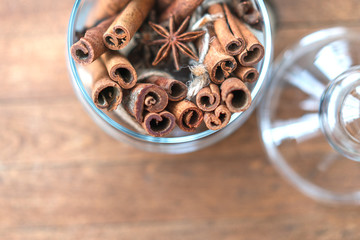 Cinnamon sticks and anise star spises in a glass jar over rustic wooden surface. Cozy still life.
