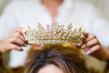 girl puts crown jewelry on the bride s head. close up