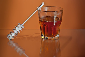Alcoholic drink with ice in transparent glasses. Wine glass with cocktail isolated on orange background. Frozen drinks on glass table. Ice in the form of an inscription - Rum.
