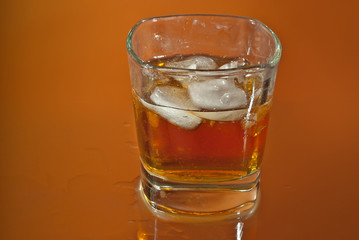 Alcoholic drink with ice in transparent glasses. Wine glass with cocktail isolated on orange background. Frozen drinks on glass table.
