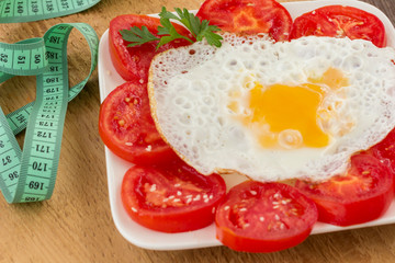 Sliced tomatoes and egg on a uncut board. Measuring tape. Low calorie diet concept. There is a place for text