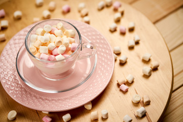 Cup with hot milk and colorful marshmallows on wooden table