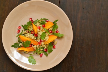 Quinoa salad with persimmon, pomegranate and fresh herbs, top view, copy space