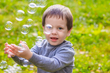 A boy on the street catches soap bubbles. Happy childhood. Children's games.
