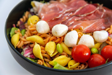 Salad made with cooked pasta, mixed green salads, cherry tomatoes, Mozzarella cheese and smoked ham...
