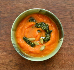 Pumpkin and carrot cream soup with cilantro sauce, seeds, top view, copy space