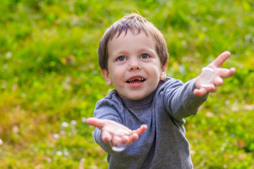 A boy on the street catches soap bubbles. Happy childhood. Children's games.