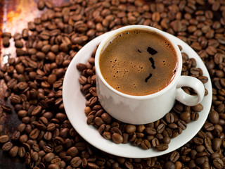 Close - up of a white Cup of coffee in coffee beansClose - up of a white Cup of coffee in coffee beans
