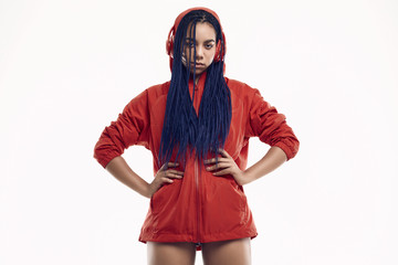African teenage girl with dreadlocks in red windbreaker listening music