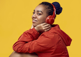 African teenage girl with dreadlocks in red windbreaker listening music