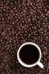 Coffee beans surrounding a coffee mug