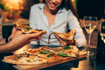 close up of people eating pizza.