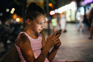 young girl using mobile phone outdoor. night scene