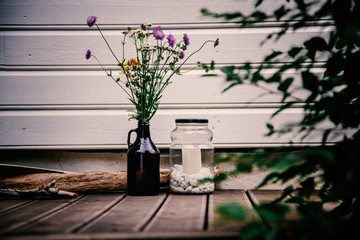 Vase with wildflowers and a glass jar with white pebbles, diine decor and decoration on the terrace