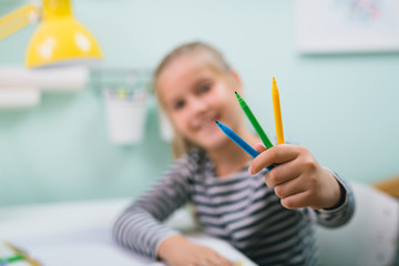 girl siting table at her room and holding felt pens