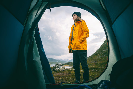 Wild camping. View from the tourist tent to the mountains in Jutunheimen park in Norway, Girl traveler in a yellow jacket