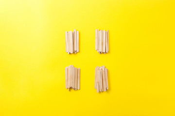 Few heap of many wooden ice cream sticks on yellow background. Concept gray crowd  and individual