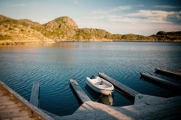 Small white boat on a wooden pier on the shore, Lofoten Islands Norway