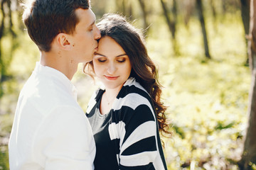 bright and happy pregnant woman walking in the park with her husband