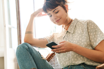 Pretty woman indoors at home using mobile phone chatting.