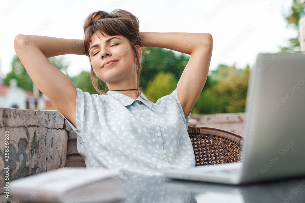 Sticker pleased young beautiful woman using laptop computer on a balcony have a rest.