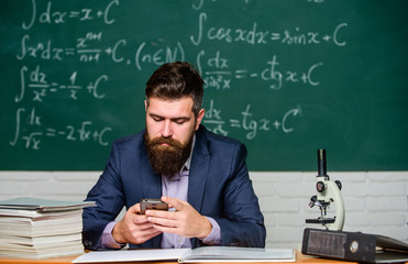 School teacher hold mobile phone chalkboard background. Teacher bearded man learn use modern...