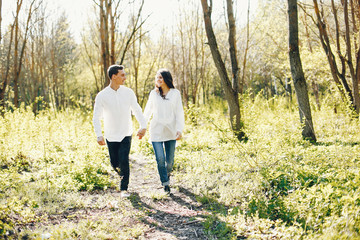 bright and happy pregnant woman walking in the park with her husband