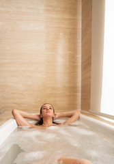Young woman laying relaxing in bathtub. Woman taking a bath