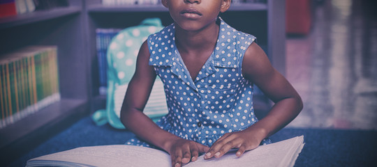 Girl reading braille book in library