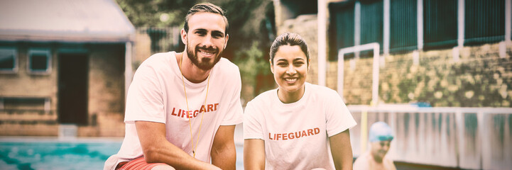 Male and female lifeguards holding rescue cans at poolside - Powered by Adobe