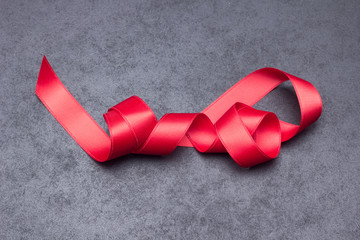 Cinta de regalo de color rojo, sobre fondo gris; lazo de regalo